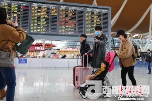 旅客帶著孩子前往辦票柜臺(tái)辦理登機(jī)手續(xù)。　殷立勤 攝