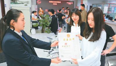 河北省承德市網(wǎng)絡(luò)代購經(jīng)營者陳晨(右)從工作人員手中接過帶有統(tǒng)一社會信用代碼的營業(yè)執(zhí)照。 劉環(huán)宇攝(人民圖片)