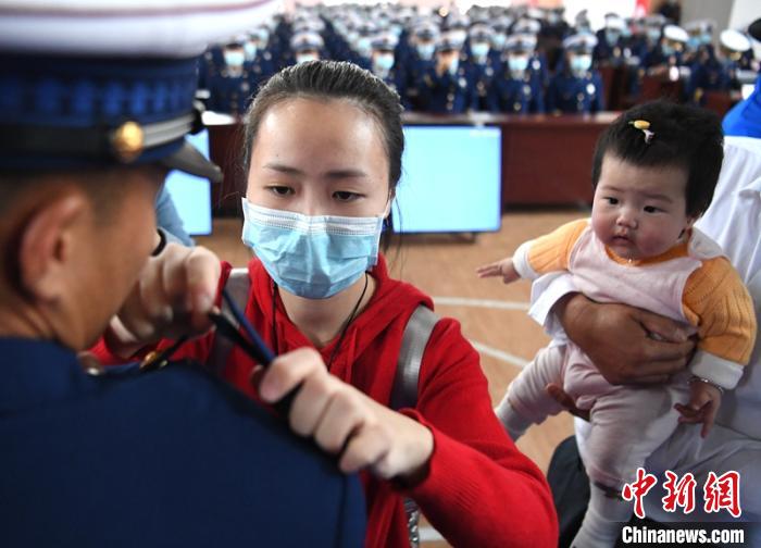 新消防員楊振的妻子彭莉與女兒現(xiàn)場見證丈夫加入“火焰藍(lán)”的神圣時刻?！⒅铱?攝